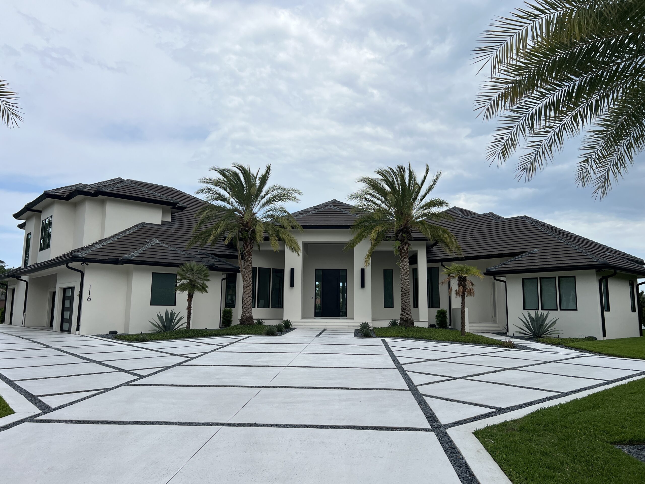 Modern luxury home with palm-lined driveway