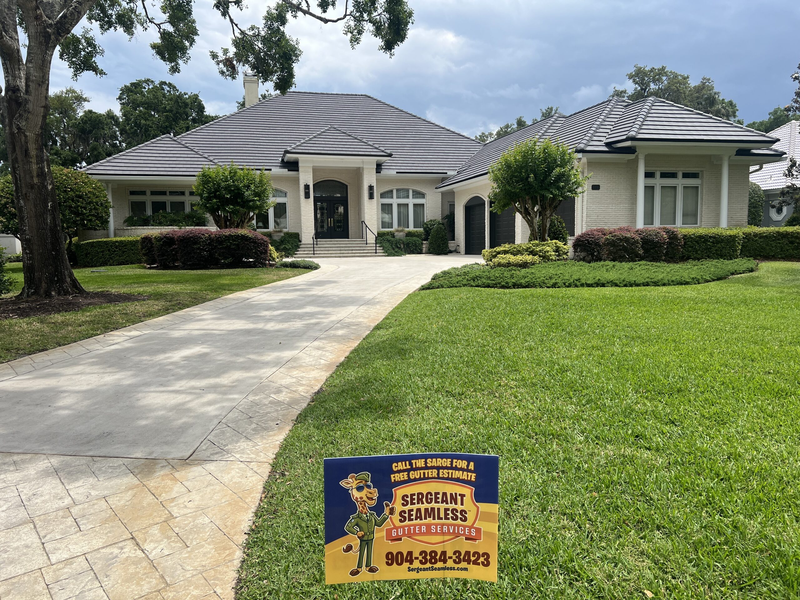 White brick house with manicured lawn and sign
