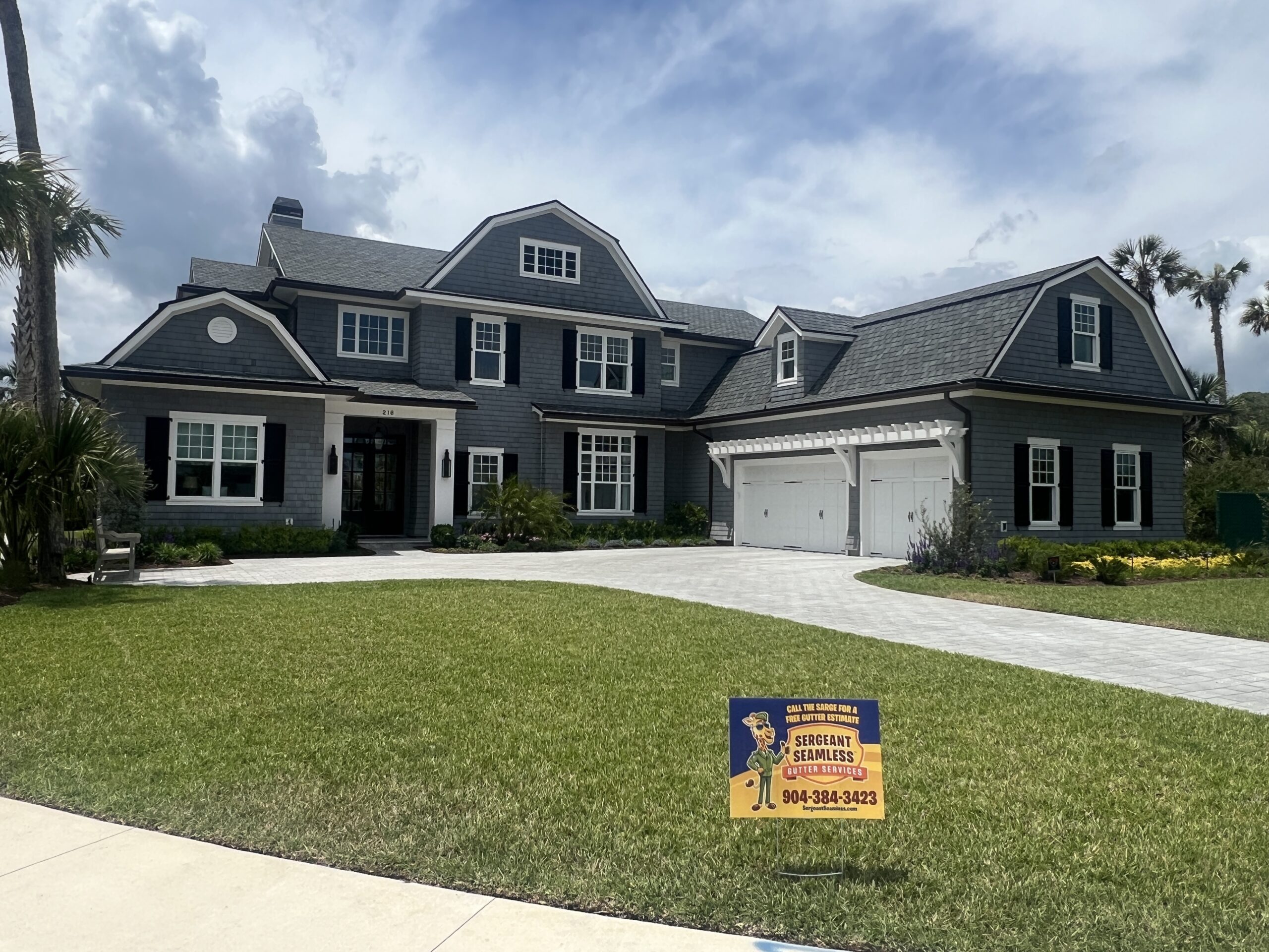 Large gray suburban house with manicured lawn