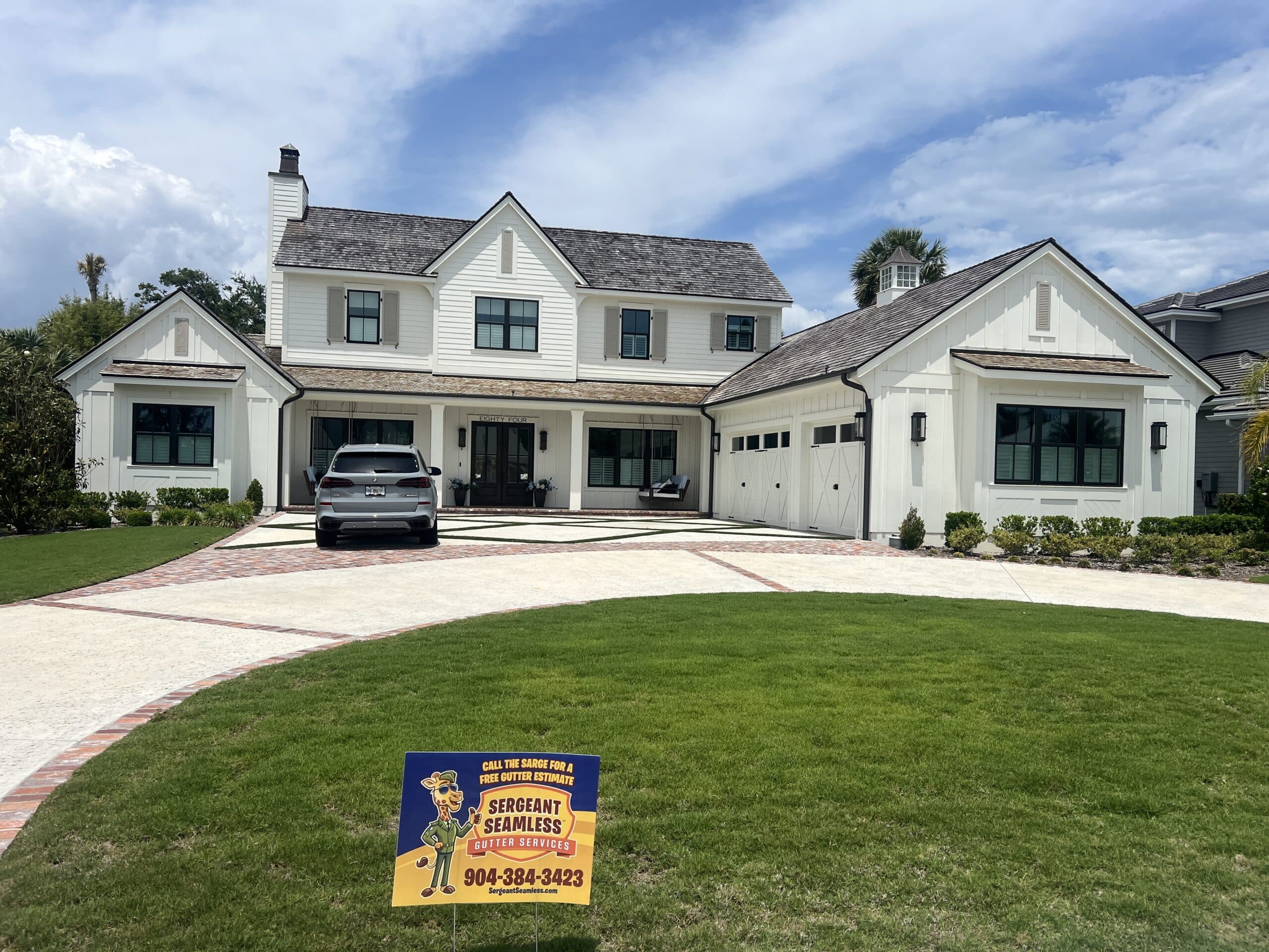 Modern white farmhouse with manicured lawn and driveway