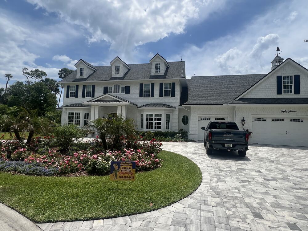 New seamless gutters on a large two-story home with a circular paver driveway
