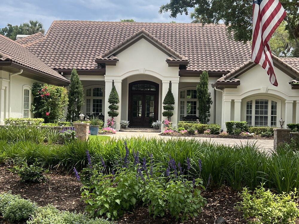 Seamless gutters and a downspout routed down a column on a tile roof home in Jacksonville, Florida